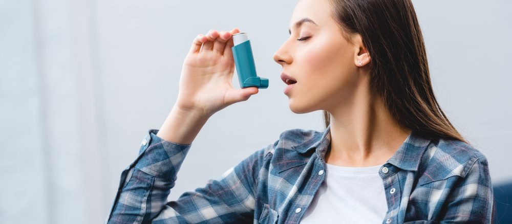 A girl using inhaler while suffering from Asthma-COPD overlap syndrome at home.