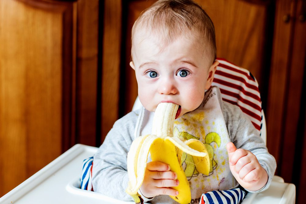 A cute baby eating banana.