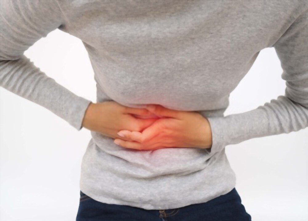 Young woman holding her stomach due to stomach pain, caused by garlic allergy