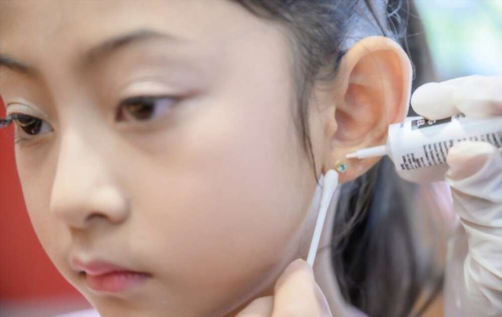 Little girl getting aftercare of ear piercing.