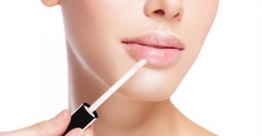 Lip Neutralization concept - Young girl is applying Moisturizing Lip Gloss
