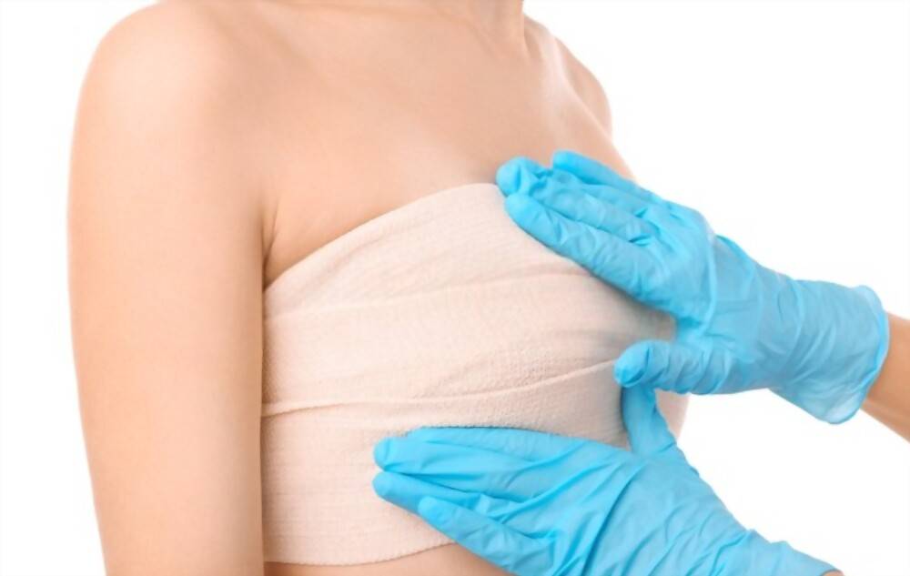 A surgeon is examining the breast for fat transfer breast augmentation.