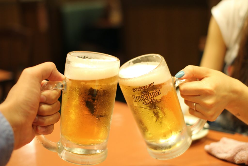 Mugs of beer in male and female hands, give the concept of beer allergy.